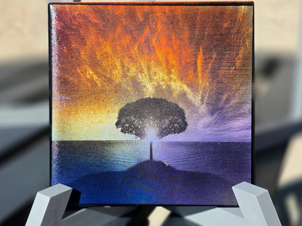 Finished HayesLabs Lone Tree artwork, laser-etched and hand-colorized, displayed on a white stand