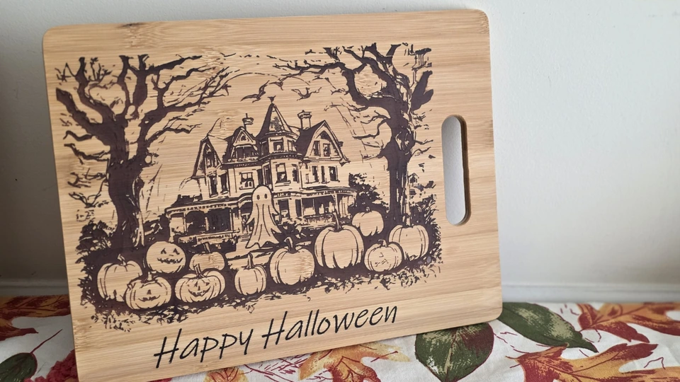 Haunted house and pumpkins laser-engraved on a Happy Halloween board